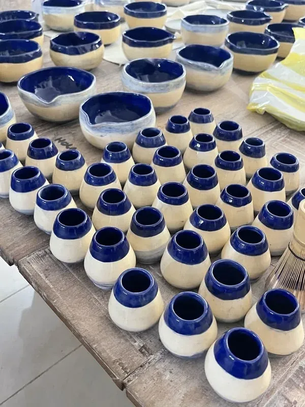 Cerámicas azules y beige apiladas mientras secan en un taller